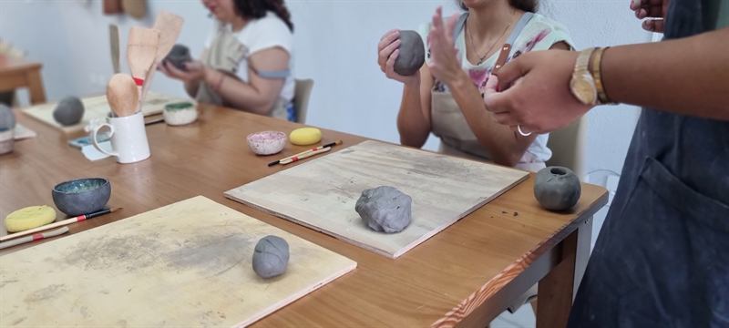 Bancada de aula com bolas de argila, tábuas de trabalho e ferramentas de modelagem