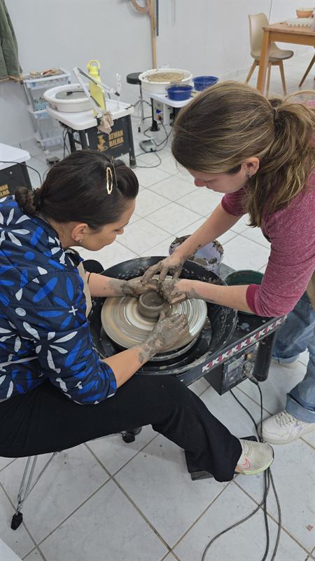 Professora orientando uma aluna no torno de cerâmica