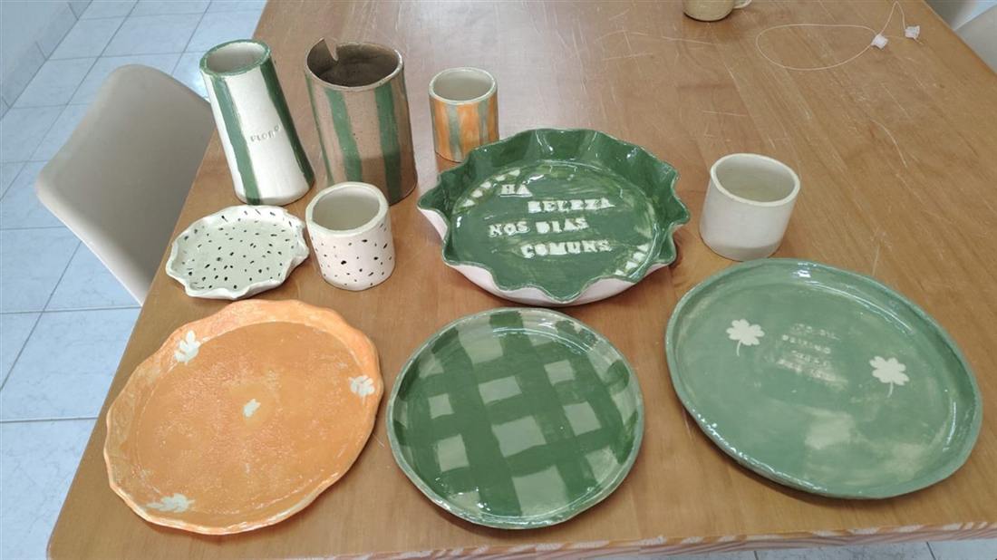 Pratos e canecas de cerâmica finalizados sobre a mesa do ateliê