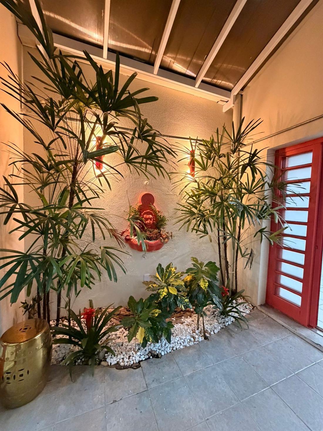 Jardim interno do ateliê com plantas e porta vermelha