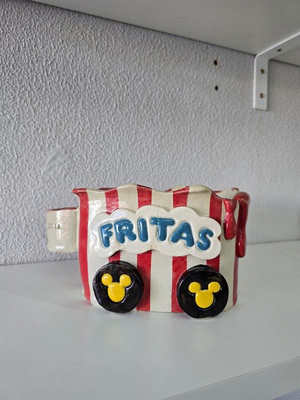 Peça de cerâmica em formato de carrinho de pipoca listrado, com a palavra Fritas e rodas com orelhas do Mickey